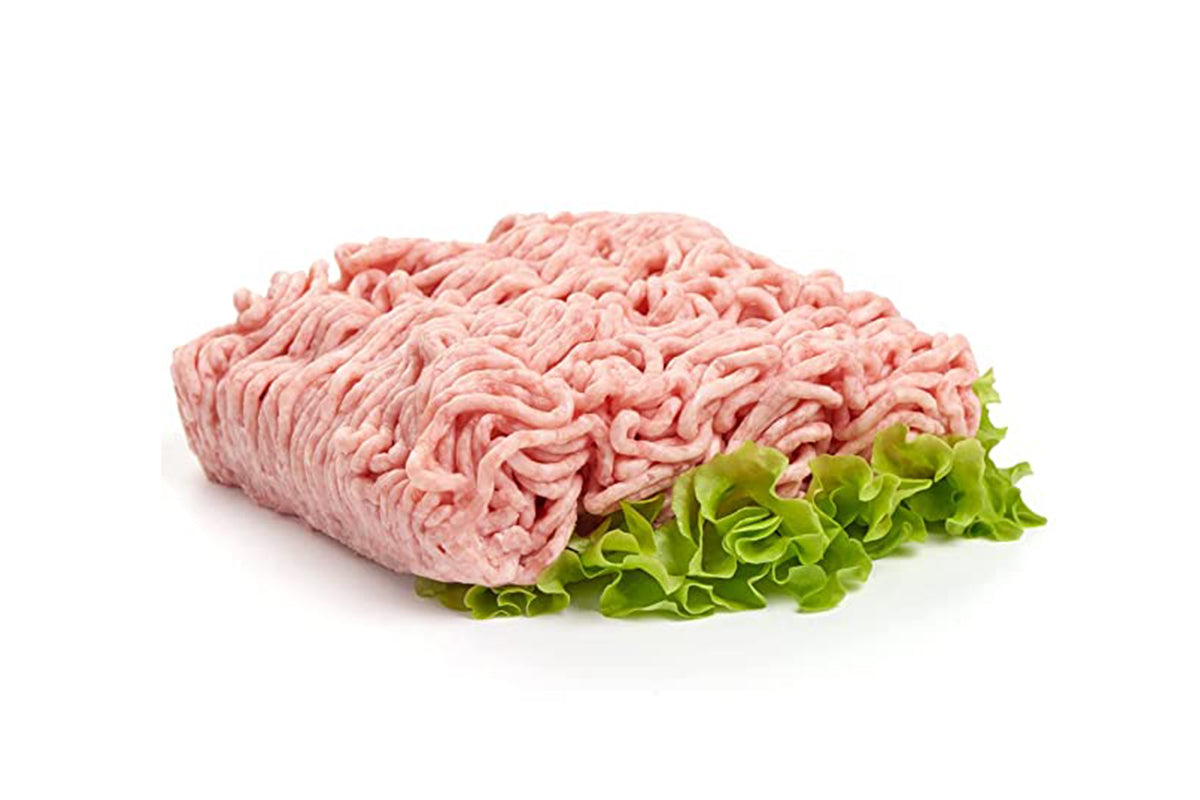 A piece of fresh halal chicken keema next to a leaf of lettuce on a white background.