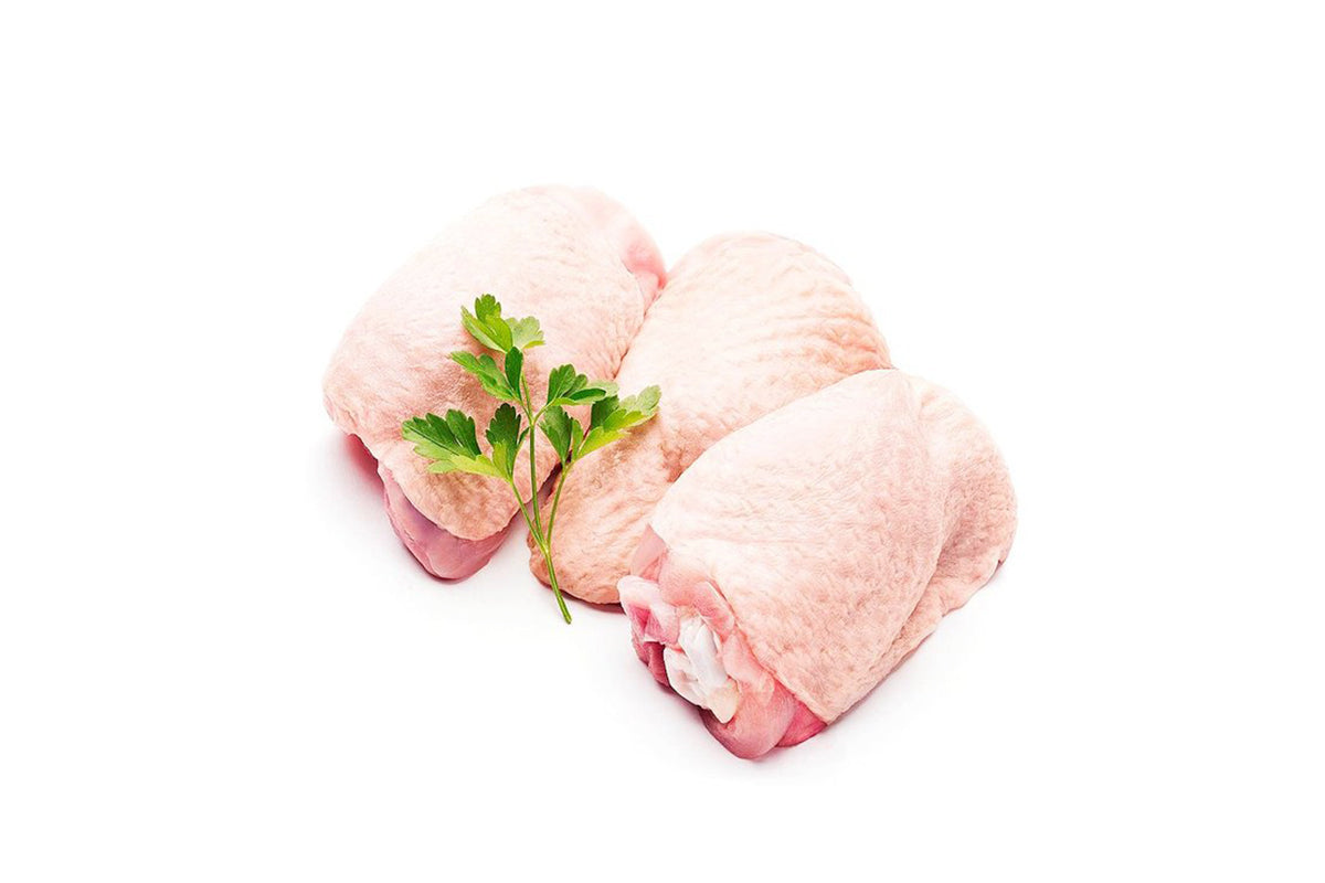 Two raw chicken thighs on a white background, one of which is partially covered with a small piece of parsley.